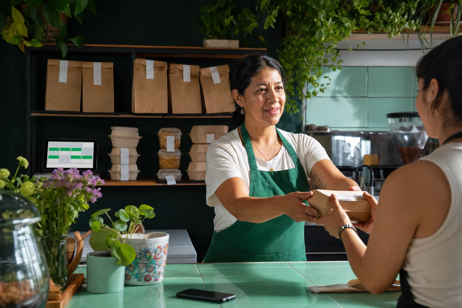 Dueña de cafetería atendiendo mientras los pedidos siguen organizados